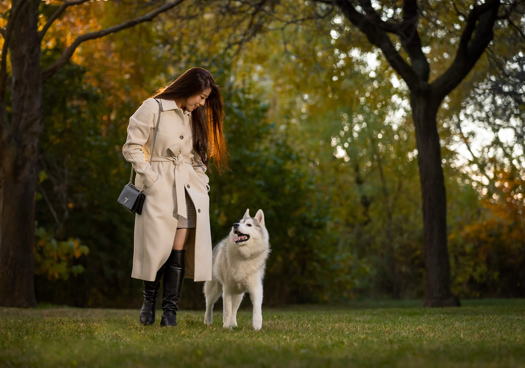 young woman in with Prada purse walking with her husky