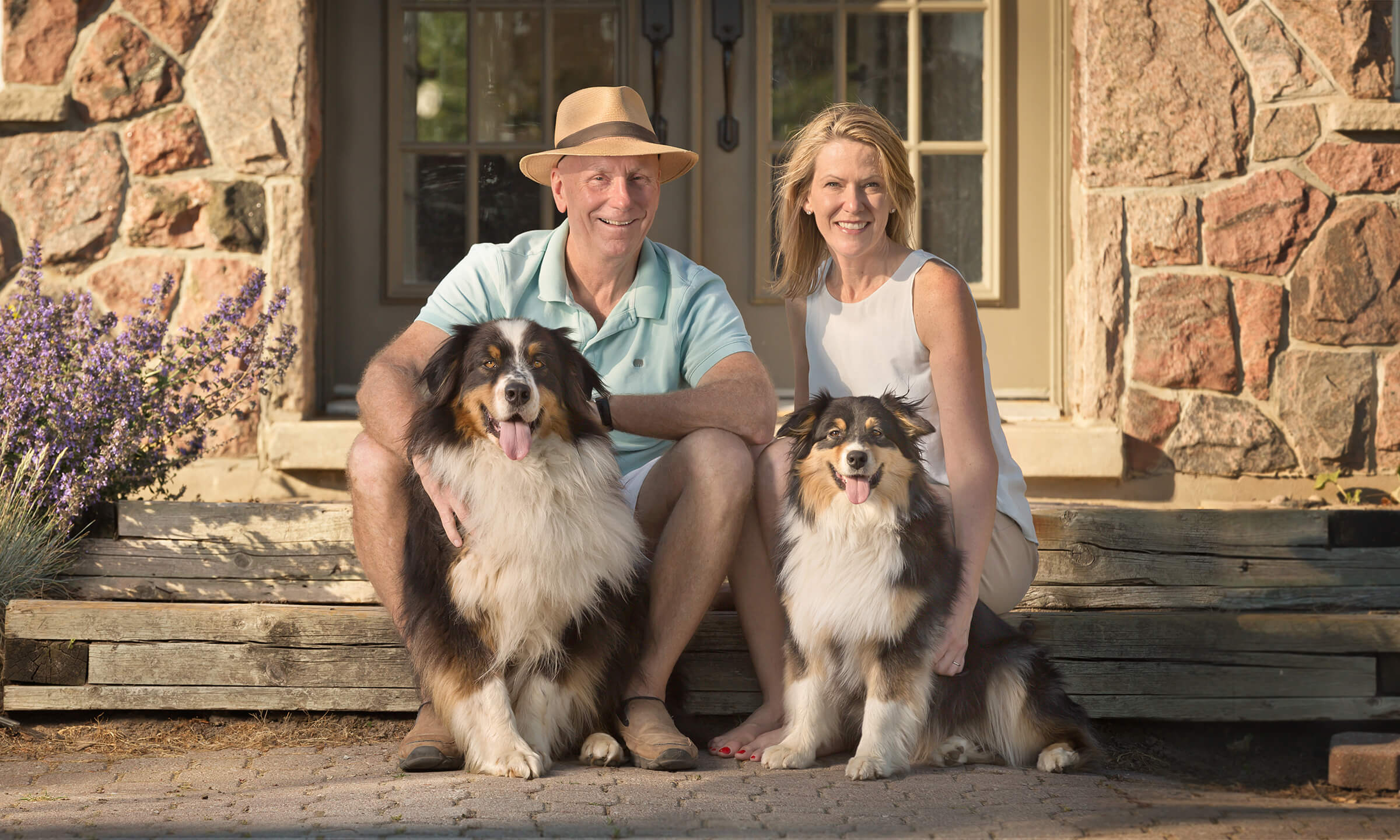 Older couple with two dogs on steps of carriage house