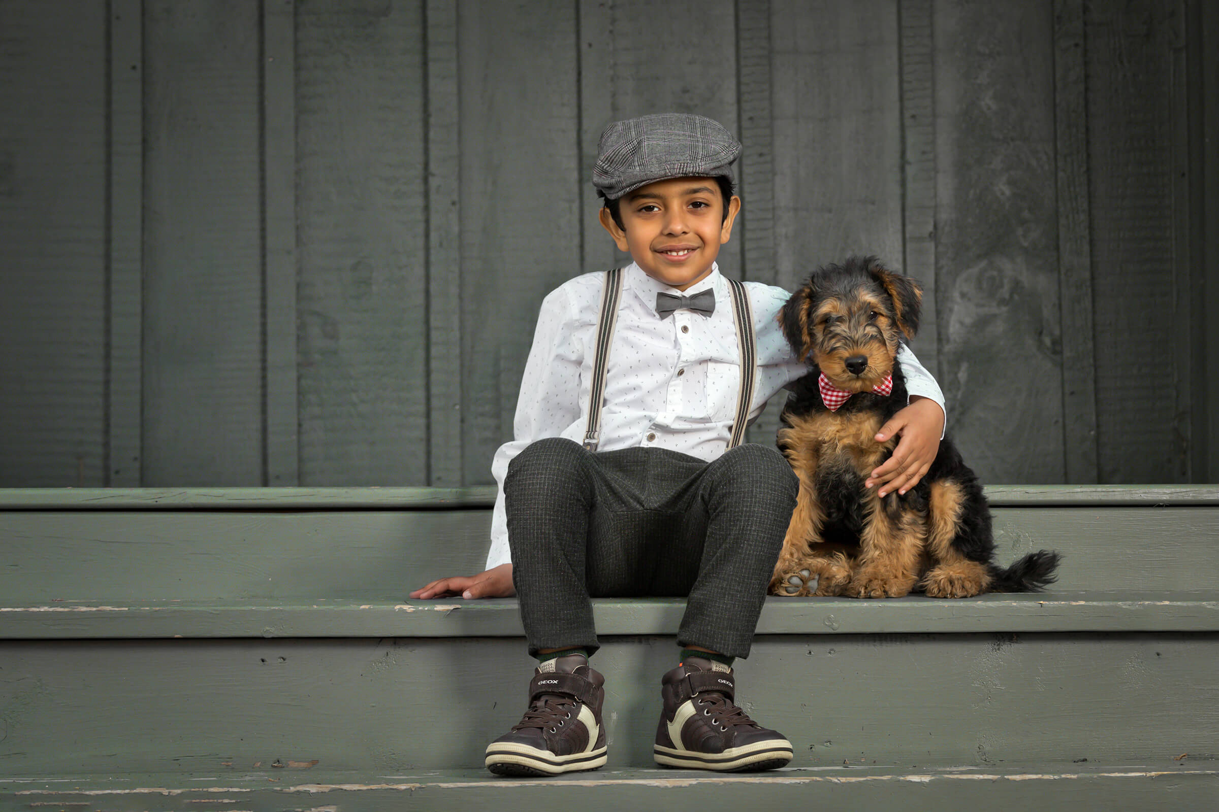 young boy and puppy sitting on front porch together