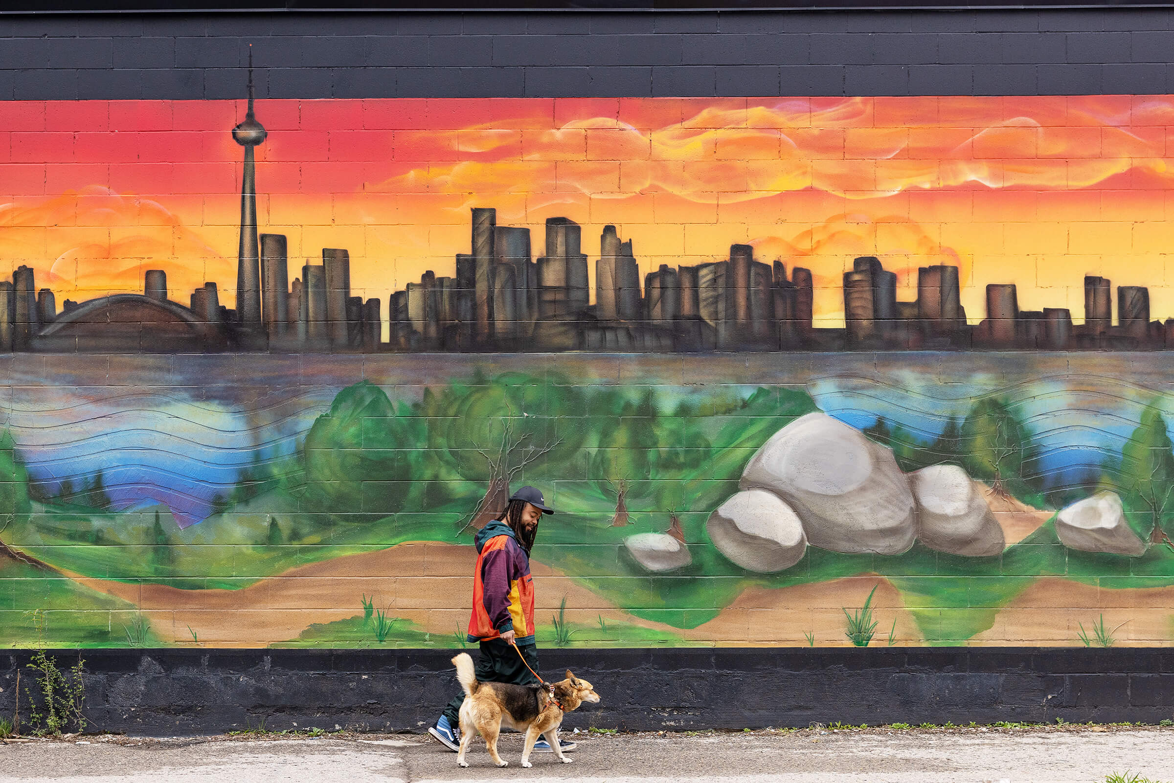 man and dog walk past Toronto mural